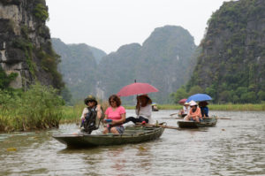 CRUISING DOWN THE NGO DONG RIVER TO THE TAM COC CAVES IN FLAT-BOTTOMED SAMPANS THAT ARE ROWED BY FOOT.