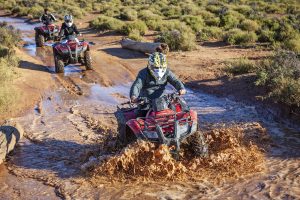 two people quad biking through mud