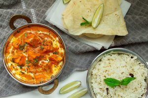 a dish with chicken stew in it alongside some rice