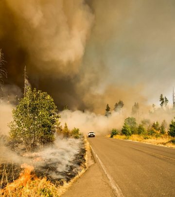 a wild fire with a car driving away from the smoke