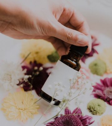 a woman holding a bottle of essential oils with a milk bath and flowers in the background