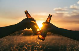 two people toasting with beer bottles