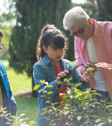 a grandfather showing his grandkid how to deadhead flowers