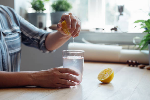 Man squeezing lemon juice into a glass of water