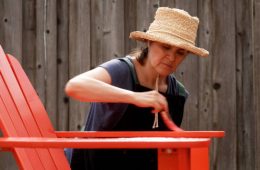 Woman Painting an outdoor chair at her backyard