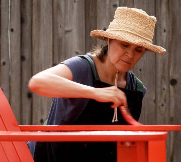 Woman Painting an outdoor chair at her backyard