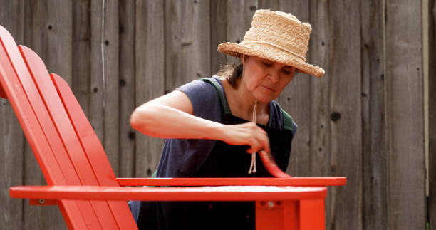Woman Painting an outdoor chair at her backyard