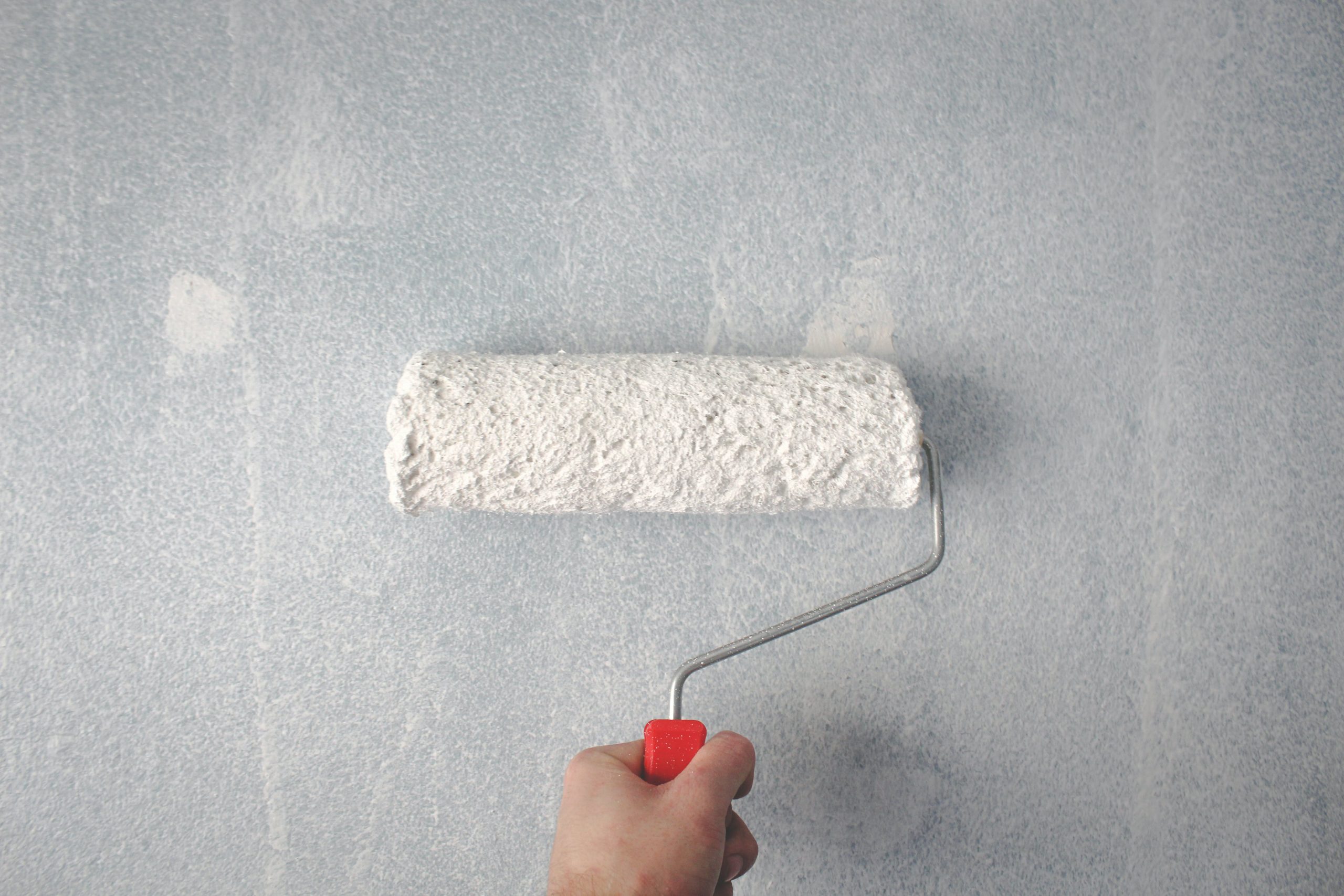 A person using a roller to paint a wall