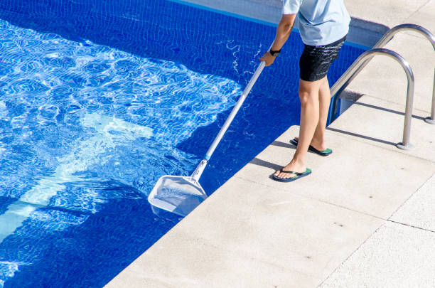 Man cleaning the swimming pool with a net