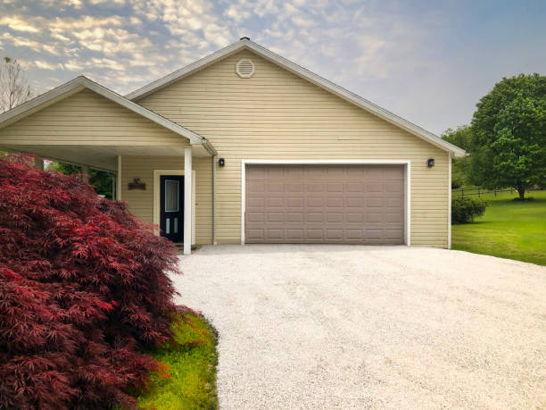 Freshly sealed gravel driveway leading to garage house.