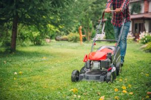 Man mowing grass in his lawn near his house