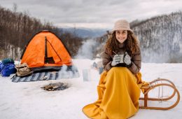 woman sitting covered with a blanket camping on snow