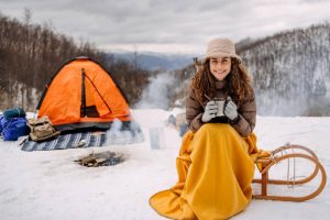 woman sitting covered with a blanket camping on snow