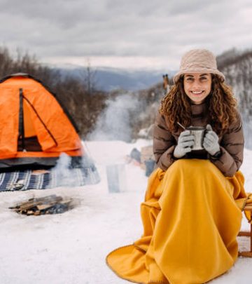 woman sitting covered with a blanket camping on snow