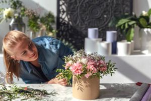Pretty woman making bouquet of pink carnations flowers for mothers day
