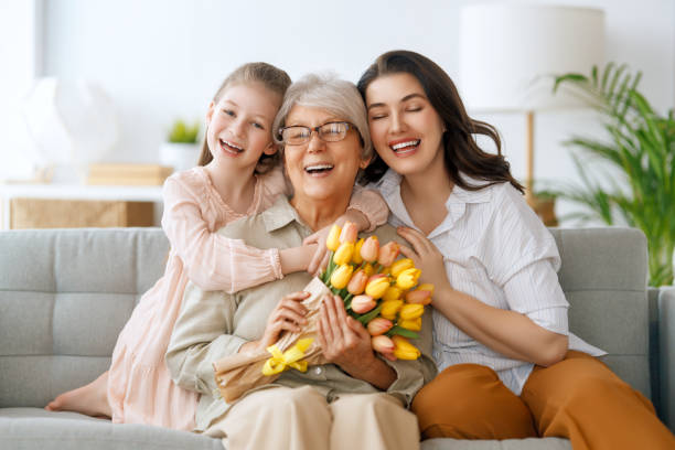 Happy mother's day. Child daughter and mother are congratulating granny giving her flowers tulips. 