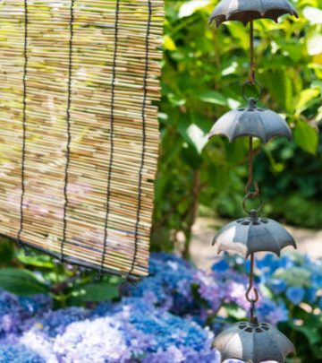 Rain chains and bamboo blind hanging before a Japanese garden