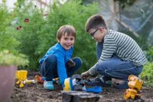 Young brothers plays in the mud with his toy truck