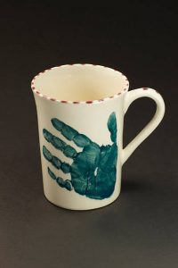 Coloured mug with an imprint of a child's hand on it.