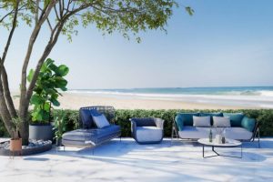 Patio with garden furniture overlooking empty beach in the summer.