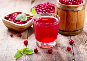 A glass of cranberry juice with fresh berries on wooden table