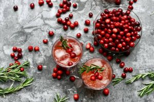 Cranberry drinks on the counter with cranberry fruits scattered all over.