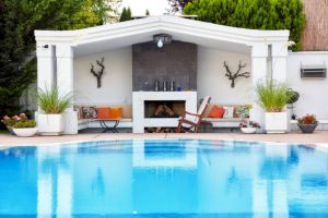 Backyard patio of a luxury residence with swimming pool and fireplace under diffuse daylight.