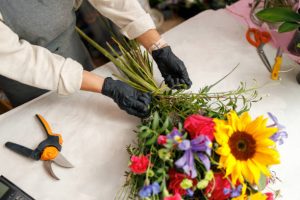 Female decorator creating beautiful bouquet at table. Lifestyle flower shop