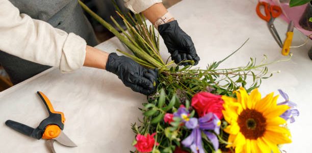 Female decorator creating beautiful bouquet at table. Lifestyle flower shop
