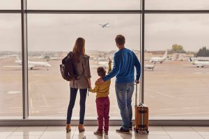 Such large aircraft. Back view shot of young family with luggage standing near window in airport before boarding
