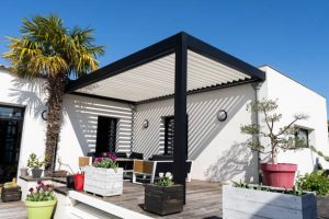 eco friendly bioclimatic aluminum pergola shade structure, awning and patio roof, garden lounge, chairs, metal grill surrounded by landscaping